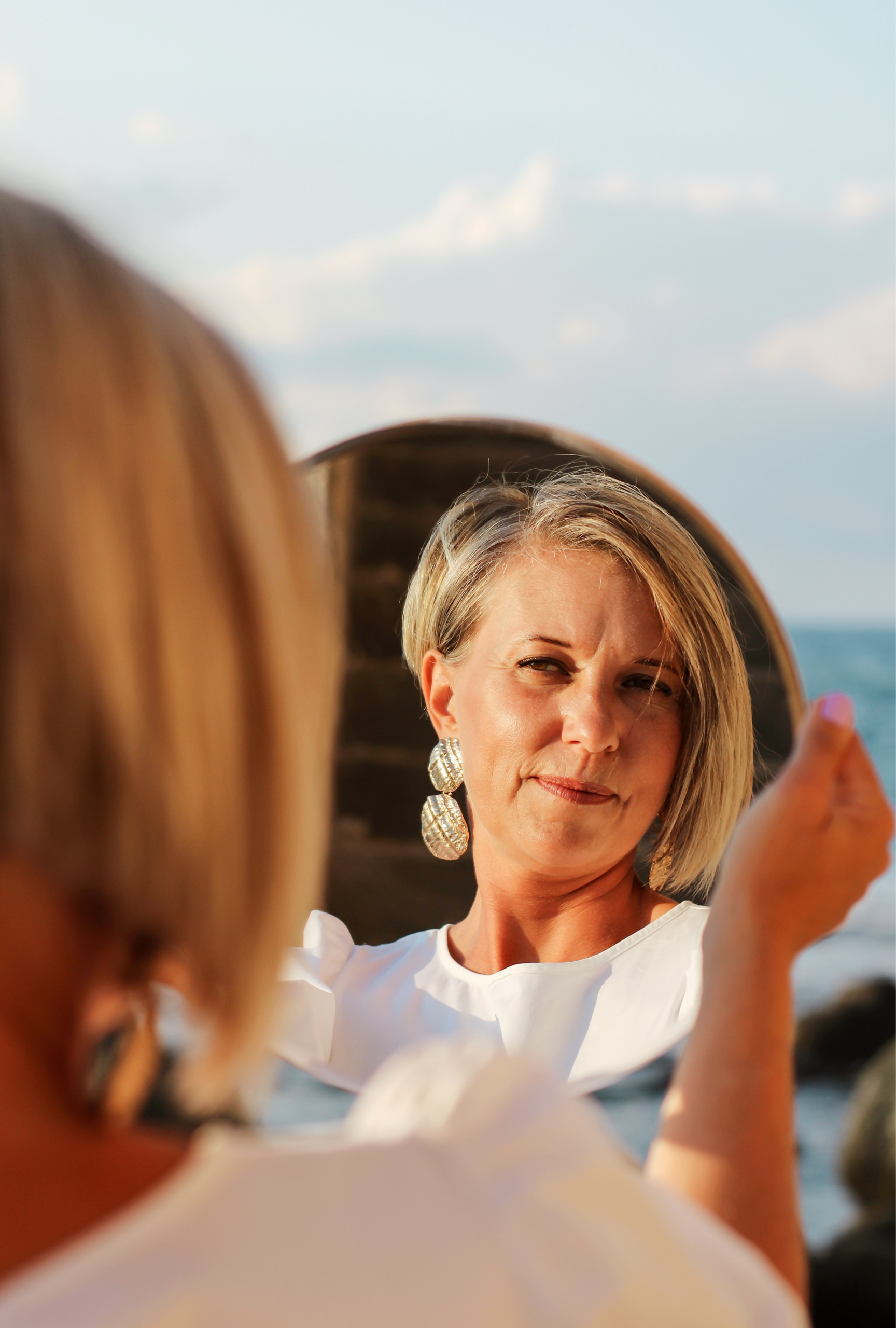 Woman looking in mirror outdoors — cosmetic surgery decision Lunara Medical Travel Canada